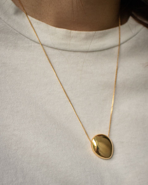 A timeless looking necklace featuring a smooth round pebble-like pendant - The Hexad Jewelry
