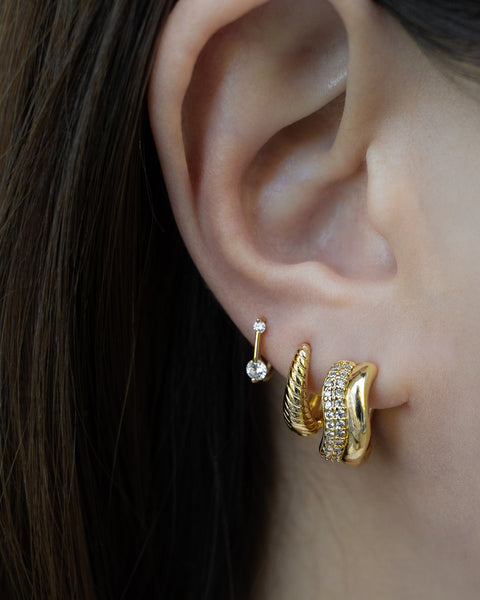 a modern stacked look in gold crafted from layerable hoop earrings and huggies