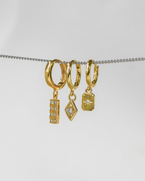 a trio of hoop earrings inspired by tarot cards with diamond and sun motifs for unique ear party