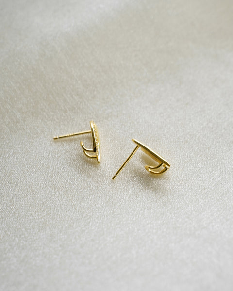 Gold earrings on a light gray background