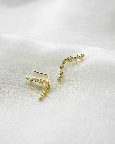 up close details of the intricate design and lovely diamonds of the hexad's just launched comet climber earrings in gold
