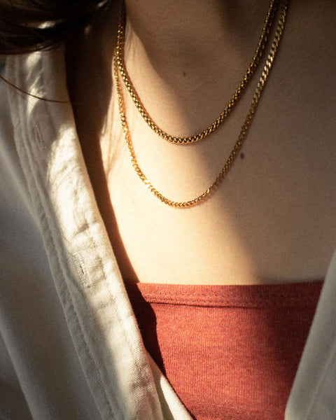Gold necklace stack with The Hexad's Woven Chain and Cuba Chain