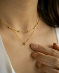 feminine neck stack featuring delicate solitaire pendant necklace and whimsical chain in gold