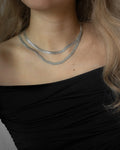layer short and long cobra chain necklaces with a low cut black blouse