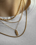 multiple gold chain necklaces layered together against a simple white tee @thehexad