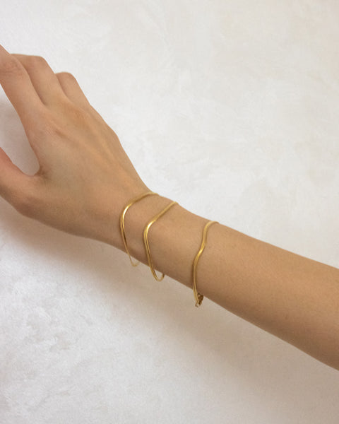 sleek gold chain reptile bracelets as worn on model's wrist